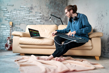 Image of male musician playing electronic piano and recording music at home studio. Concept of domestic hobby, entertainment and leisure. Young creative songwriter man 