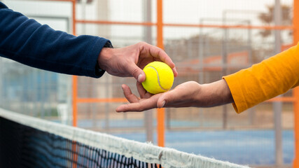 Male hand of paddel player receiving a tennis ball from opponent, over the net.
