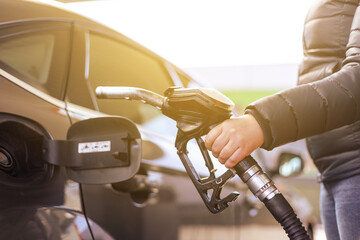 High prices of petrol and diesel fuel ath the petrol station, young woman refueling the car,...