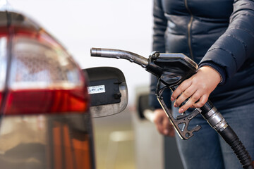 High prices of petrol and diesel fuel ath the petrol station, young woman refueling the car,...