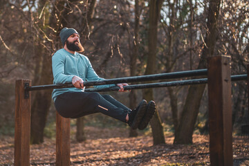 Man enjoys  exercise push- ups on parallel bars in the park.