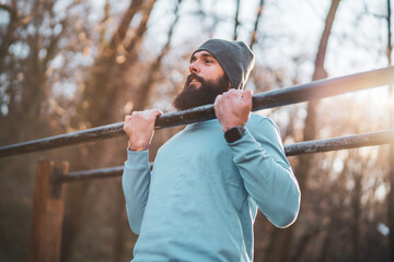 Man is  exercising  pull -ups  in the park.