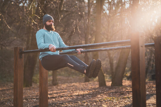 Man enjoys  exercise push- ups on parallel bars in the park.