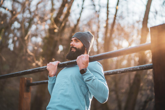 Man is  exercising  pull -ups  in the park.