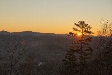 Sunset over the mountains with a beautiful orange glow and southern pines trees in the mountain forest