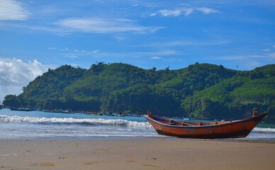 Fototapeta na wymiar Traditional wooden fishing boats and beautiful hilly beach in East Java province, Indonesia. boat background on the beach, beautiful Indonesian beaches. beach background.