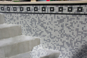 Tiles being applied to refurbish a swimming pool.