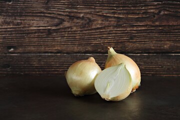 Fresh half and whole onions on dark wooden background. Selective focus