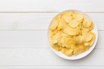 Potato chips on bowl isolated on colored background. Delicious crispy potato chips in bowl. Space...