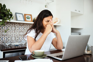 I just need a minute. Shot of a young woman looking stressed out while working on a laptop at home.
