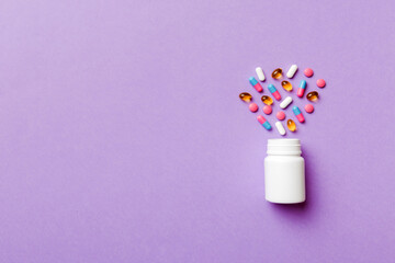 Multicolored pills and capsules in plastic bottle on Colored background, copy space. Many different various medicine tablets and pills, vitamin and nutritional supplements concept