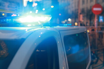 Blue lights on the roof of a police car with the background out of focus and lights with bokeh effect	