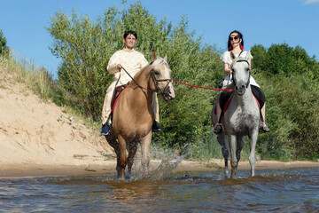 Fototapeta na wymiar a guy and a girl on horseback on a river on a sunny day