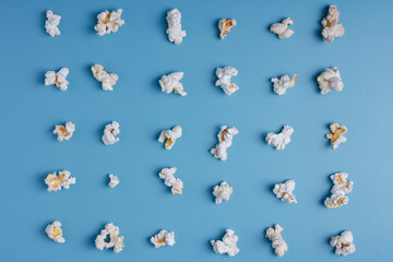 Fototapeta na wymiar Popcorn lay out on blue background, top view. Food pattern