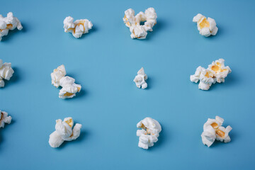 Fototapeta na wymiar Popcorn lay out on blue background, close up shot. Food pattern