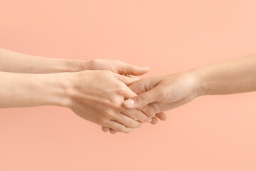 Women holding hands together on color background