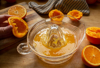 Making Freshly Squeezed Orange Juice with a Manual Citrus Press - obrazy, fototapety, plakaty