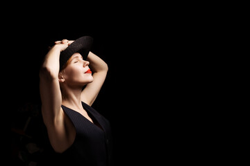 Middle age woman with relaxed pose. A woman in her forties in a black hat. Side view. Black background. Banner. Place for text.