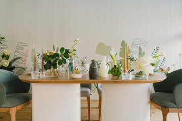 Coziness and style. Modern event design. Table setting at wedding reception. Floral compositions with beautiful flowers and greenery, candles, laying and plates on decorated table.