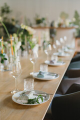 Coziness and style. Modern event design. Table setting at wedding reception. Floral compositions with beautiful flowers and greenery, candles, laying and plates on decorated table.