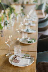 Coziness and style. Modern event design. Table setting at wedding reception. Floral compositions with beautiful flowers and greenery, candles, laying and plates on decorated table.