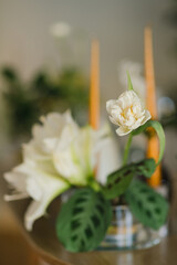Coziness and style. Modern event design. Table setting at wedding reception. Floral compositions with beautiful flowers and greenery, candles, laying and plates on decorated table.