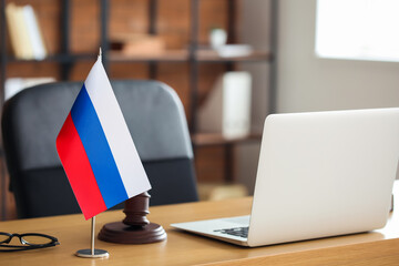Russian flag, eyeglasses, judge gavel and modern laptop on table in office