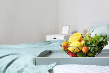 Tray with fruit basket on bed in room