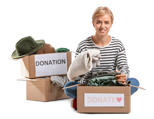 Young woman putting clothes in box for donation on white background