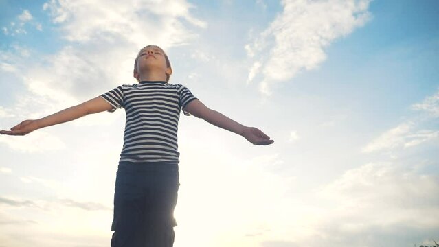 boy prays pulls hands to the sky against a blue sky. child concept lifestyle faith religion and happy family. kid son hands to the side against the blue sky jew praying to god. worship and gratitude
