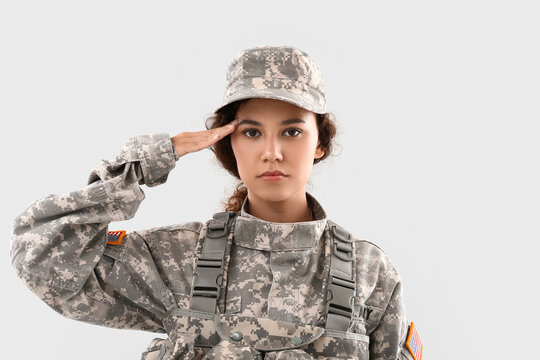 Saluting African-American female soldier on light background