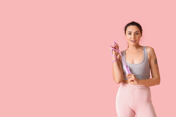 Sporty young woman with skipping rope on color background