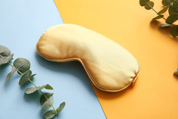 Sleep mask and eucalyptus branches on color background