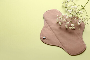 Reusable menstrual pad and flowers on green background © Pixel-Shot
