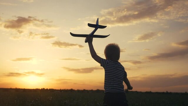 boy kid run in the park across the field play with an toy airplane in his hand a silhouette at sunset wants to be an astronaut lifestyle pilot. dream kid concept. child run on wheat play with toy