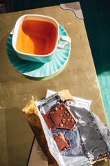 afternoon tea in square teal teacup and saucer with chocolate in gold wrapper