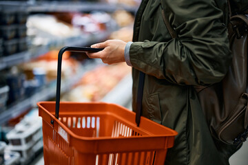 Close-up of woman using shopping basket while buying in grocery store.