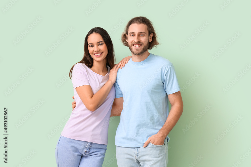 Wall mural Young couple in stylish t-shirts on green background - Wall murals