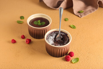 Ramekins with tasty lava cakes and raspberries on color background