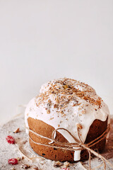 Easter cake decorated with icing white and bale rope on a wooden board with dried fruits and flour on a light background