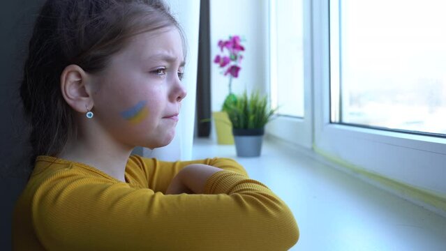 Upset Ukrainian girl kid crying protesting war conflict. Crisis, peace, stop aggression, child against Russian war