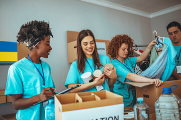 Charity workers placing food into donation boxes for a community outreach food drive of support and help people in Ukraine. Group of volunteers preparing food donations for people in need in Ukraine