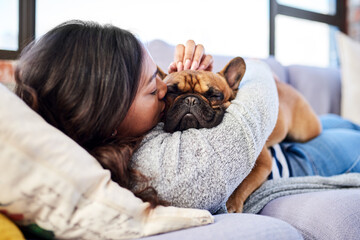 Sometimes the smallest things take up the most space in your heart. Shot of a young woman relaxing with her dog at home.