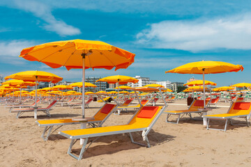 Bright orange parasols and deck chairs on the beach in Rimini, Italy. 