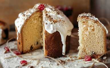 Cut panetone piece with cranberries and nuts on a wooden table crushed with flour. Painted quail egg. Black background. Copyspace