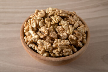 Bowl full of peeled walnuts on a wooden background,top view	