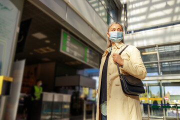 Woman in protective face mask standing in airport terminal