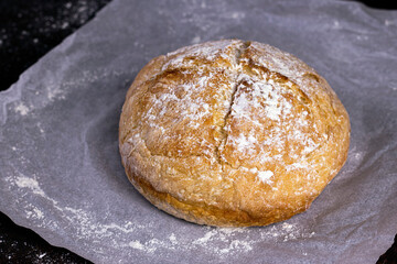 Fresh homemade crisp bread. Healthy baked bread on Kraft paper over black rustic wooden table.