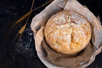 Fresh homemade crisp bread on Kraft paper with rye sticks over black table. Healthy baked bread on...