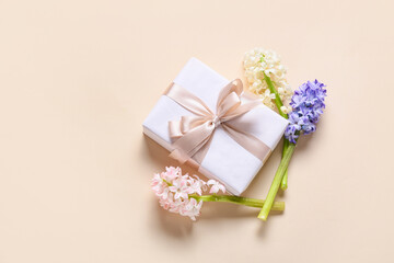 Beautiful gift box and hyacinth flowers on color background